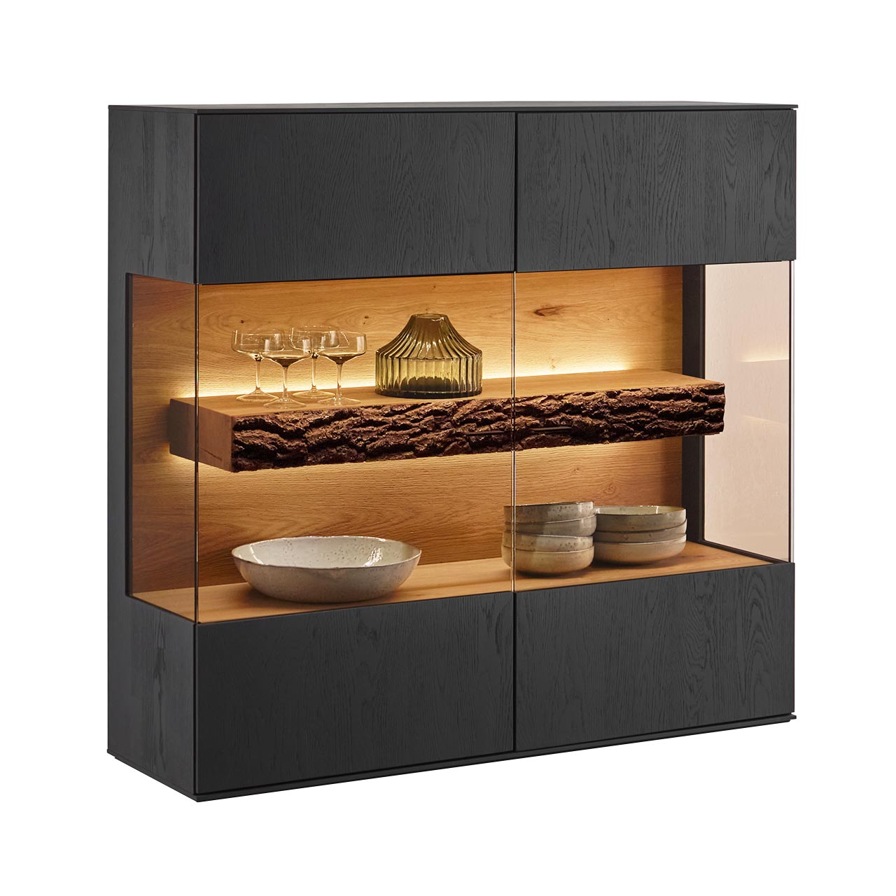 Modernes quadratisches Highboard aus massiver Kerneiche Natur, anthrazit gebeizt, mit mittigem, über Eck verlaufendem, beleuchtetem Glasausschnitt und sichtbarem Rindenboden.