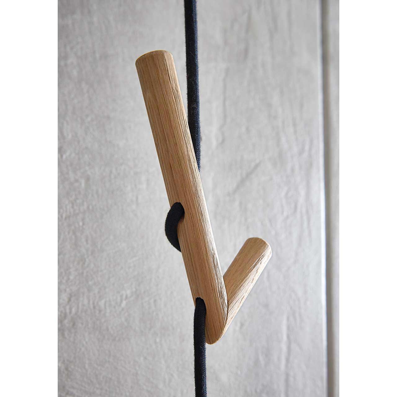 Detailaufnahme eines abgerundeten Holzkleiderhakens, der in ein schwarzes Seil der Wandgarderobe SALVO Nr. 9011 eingeflochten ist.