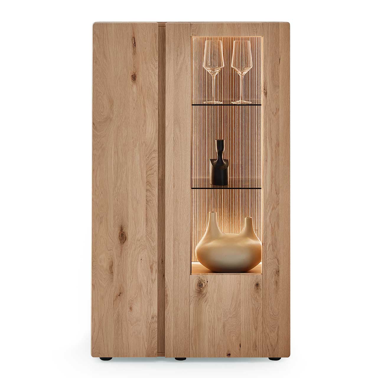 Edles Highboard aus massiver Kerneiche Natur mit einer Holztür links und einer beleuchteten Glas-/Holztür rechts, dahinter sichtbar die edel geschroppte Rückwand und die Glasböden - in Frontansicht. 