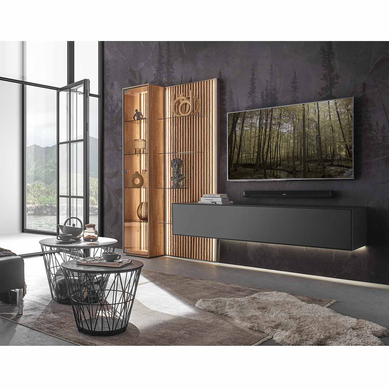 Modernes Wohnzimmer mit Fernseher und moderner dreiteiliger Wohnwand aus massivem Holz: Ein schlichtes Hängelowboard anthrazit lackiert, eine Standvitrine und ein Wandpaneel mit hellen Holzlamellen und Glas – vor dunkelgrauer Wand.