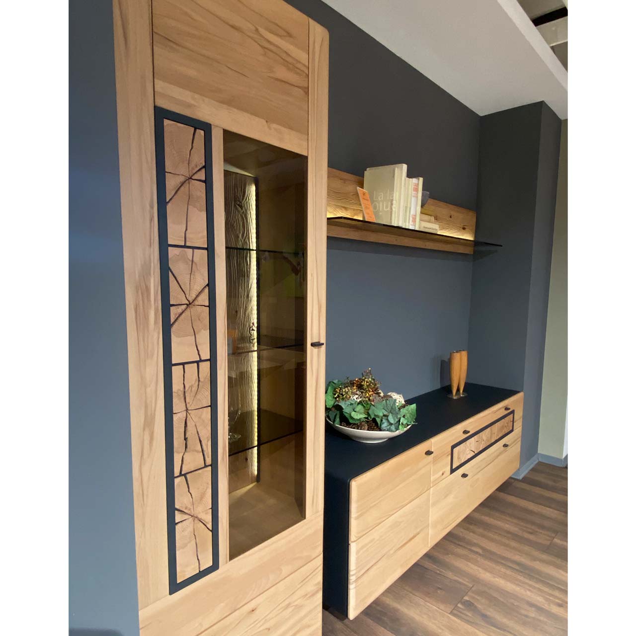 Dreiteilige Wohnwand aus massiver Kernbuche gebürstet: Hochvitrine mit Holz/Glastür und Hirnholzscheiben, Lowboard mit Tür und zwei Schubkästen und Hirnholzscheiben, darüber hängendes Wandpaneel mit Glasablage - in Seitenansicht.