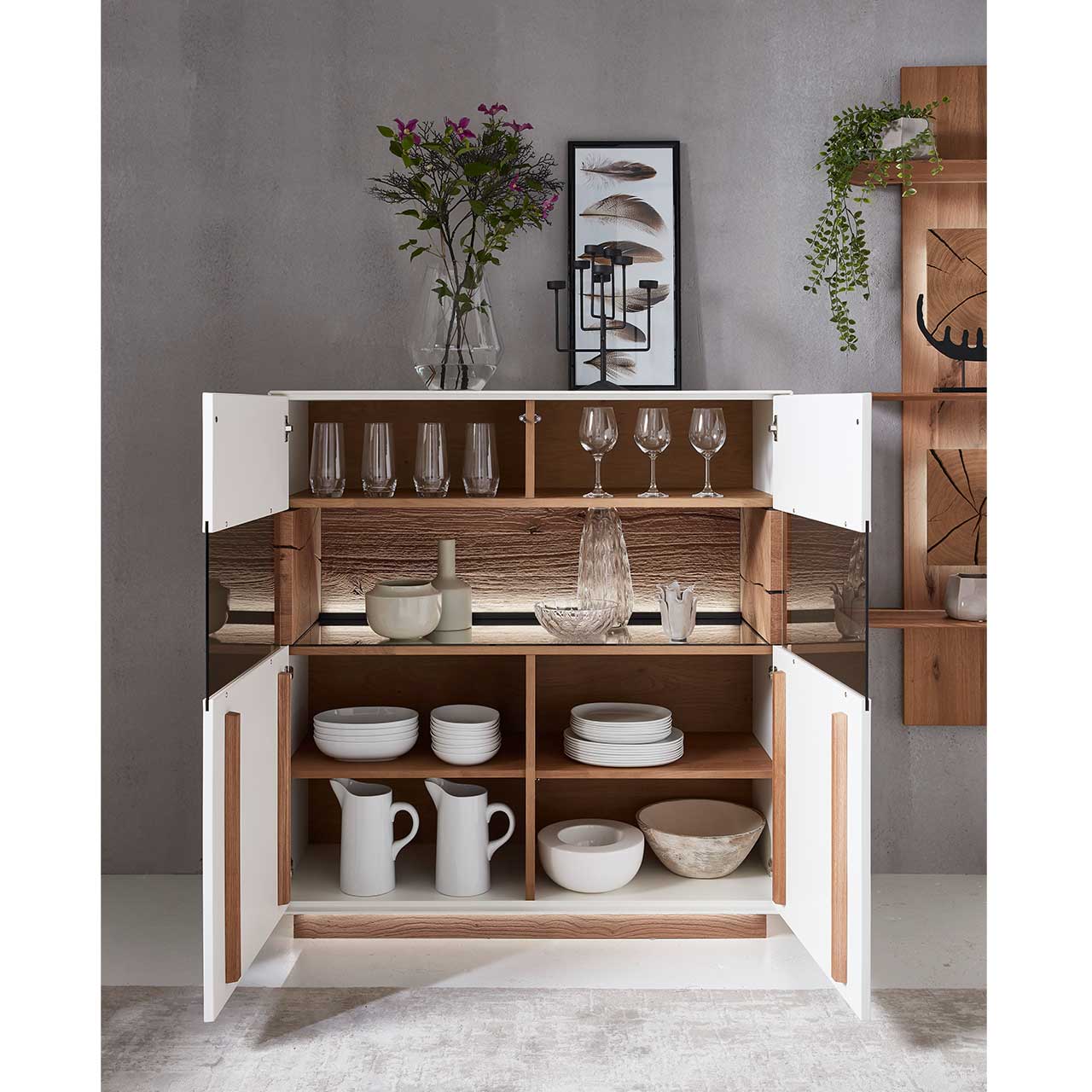 Geöffnetes Highboard in Lack weiß mit Holzakzenten, mit Tellern und Gläsern darin