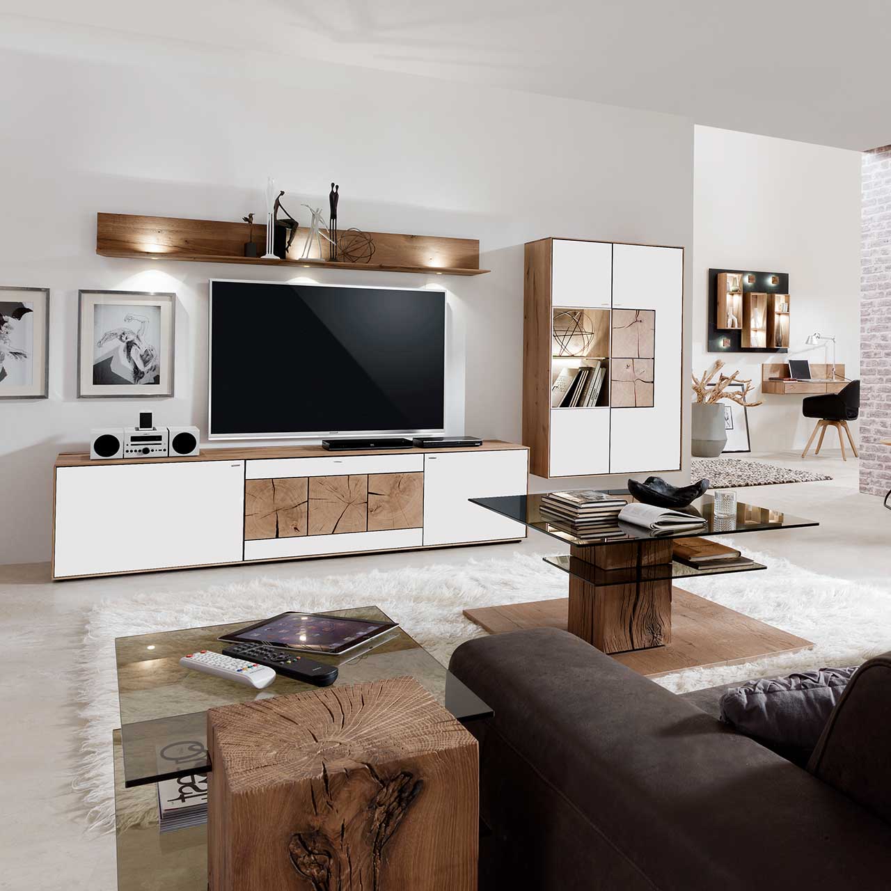 Wohnzimmer mit moderner dreiteiliger Massivholz Wohnwand mit Mattglas weiß Fronten und dekorativen Hirnholzscheiben: Langes Lowboard mit Hirnholz und Kufen, Wandpaneel mit Regalböden, Highboard mit beleuchtetem Glasausschnitt und Hirnholz.