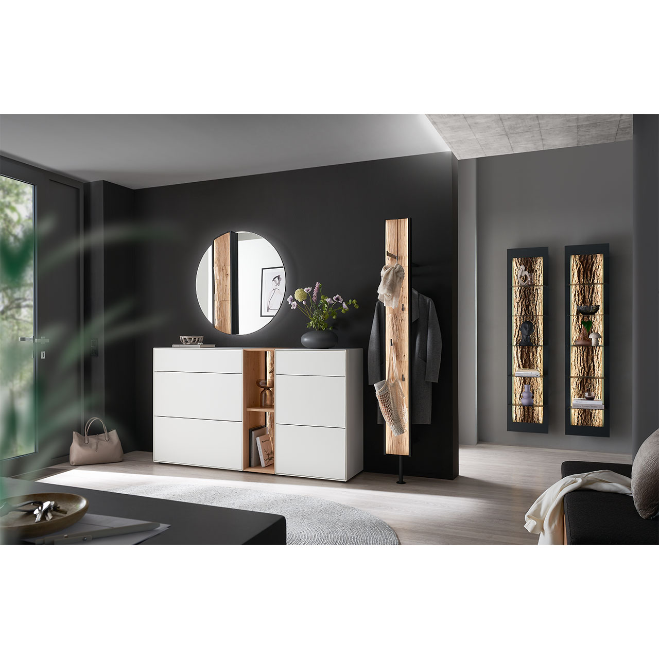 Milieubild Hartmann SALVO 8550G -  Garderobe Nr. V108S - Kernbirke weiß Lack, Kerneiche Natur, Spaltholz Flur mit modernen Garderobenmöbeln aus Kernbirke und Kerneiche Natur: Regalelement mit Spaltholz-Rückwand zwischen zwei weiß lackierten Stauraumschränken, dazu ein Garderobenpaneel und ein runder Spiegel mit Spaltholz-Akzent.