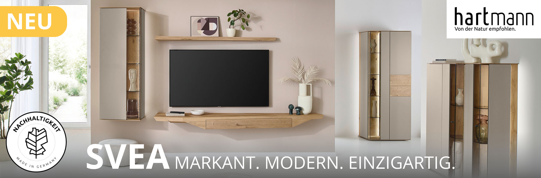 Hartmann Möbel - Möbelserie SVEA - Wohn-/Esszimmermöbel - Kerneiche Natur und Lack Sand Hartmann SVEA - Massivholzmöbel aus Kerneiche Natur kombiniert mit Lack Sand und Riffholz. Ambientebild zeigt asymmetrisches Hängelowboard, Hängevitrine und Wandboard. Davor passendes Highboard mit Glastüren, dahinter Standvitrine.