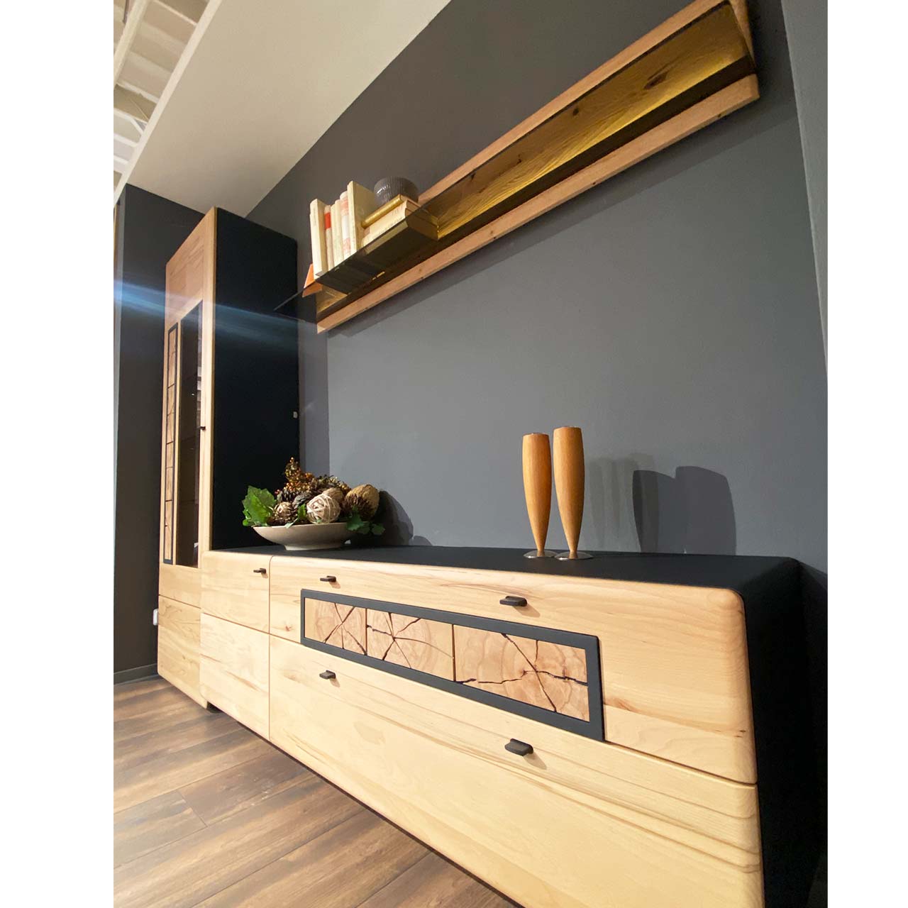 Dreiteilige Wohnwand aus massiver Kernbuche gebürstet: Hochvitrine mit Holz/Glastür und Hirnholzscheiben, Lowboard mit Tür und zwei Schubkästen und Hirnholzscheiben, darüber hängendes Wandpaneel mit Glasablage - in Seitenansicht.