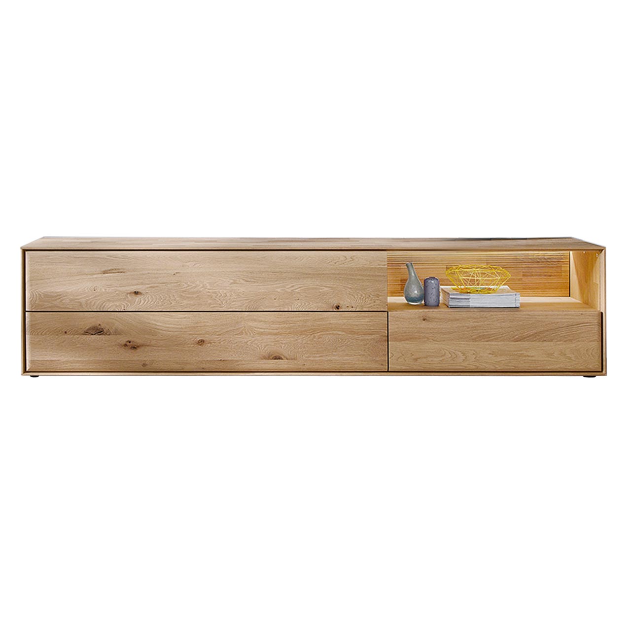 Hartmann VALA - Lowboard 8640-3241 - Kerneiche Natur Modernes Lowboard aus massiver Kerneiche Natur mit zwei Schubkästen unten, einer beleuchteten Nische mit geschroppter Rückwand rechts und einer Klappe links - in Frontansicht.