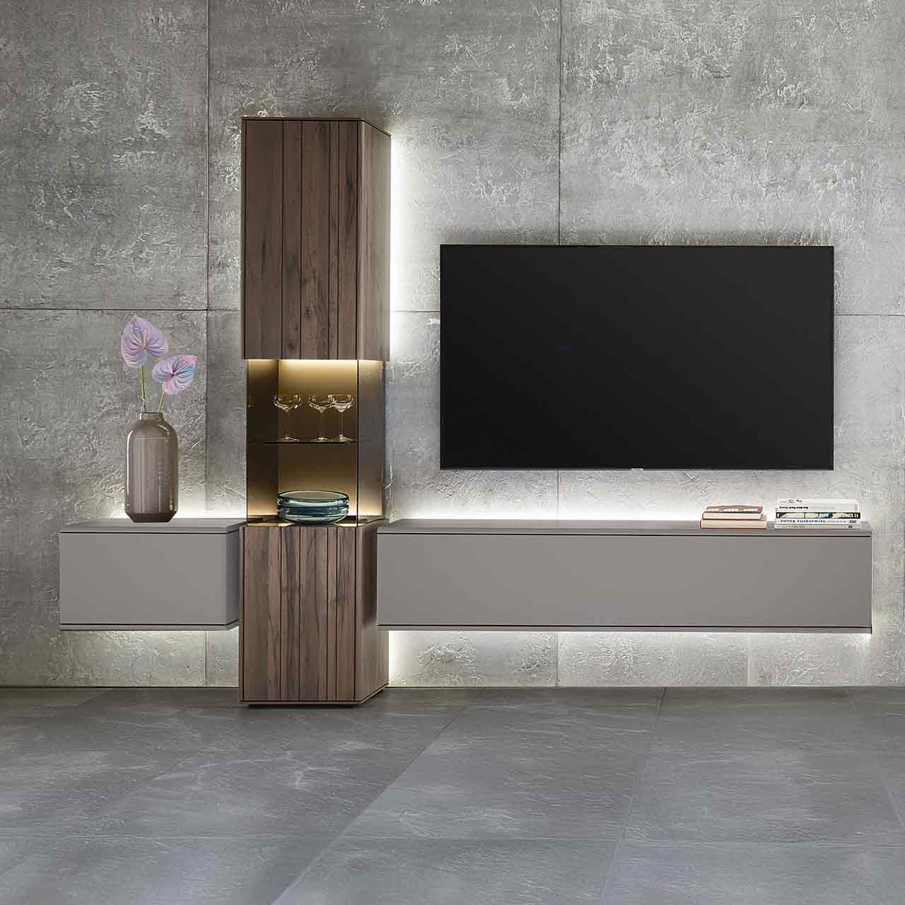 Moderne, dreiteilige Massivholz-Wohnwand bestehend aus einer Standvitrine in dunkelbraunem Holz mit Maserung und beleuchtetem Glasausschnitt, rechts und links davon zwei Hängelowboards in Lack Sand.