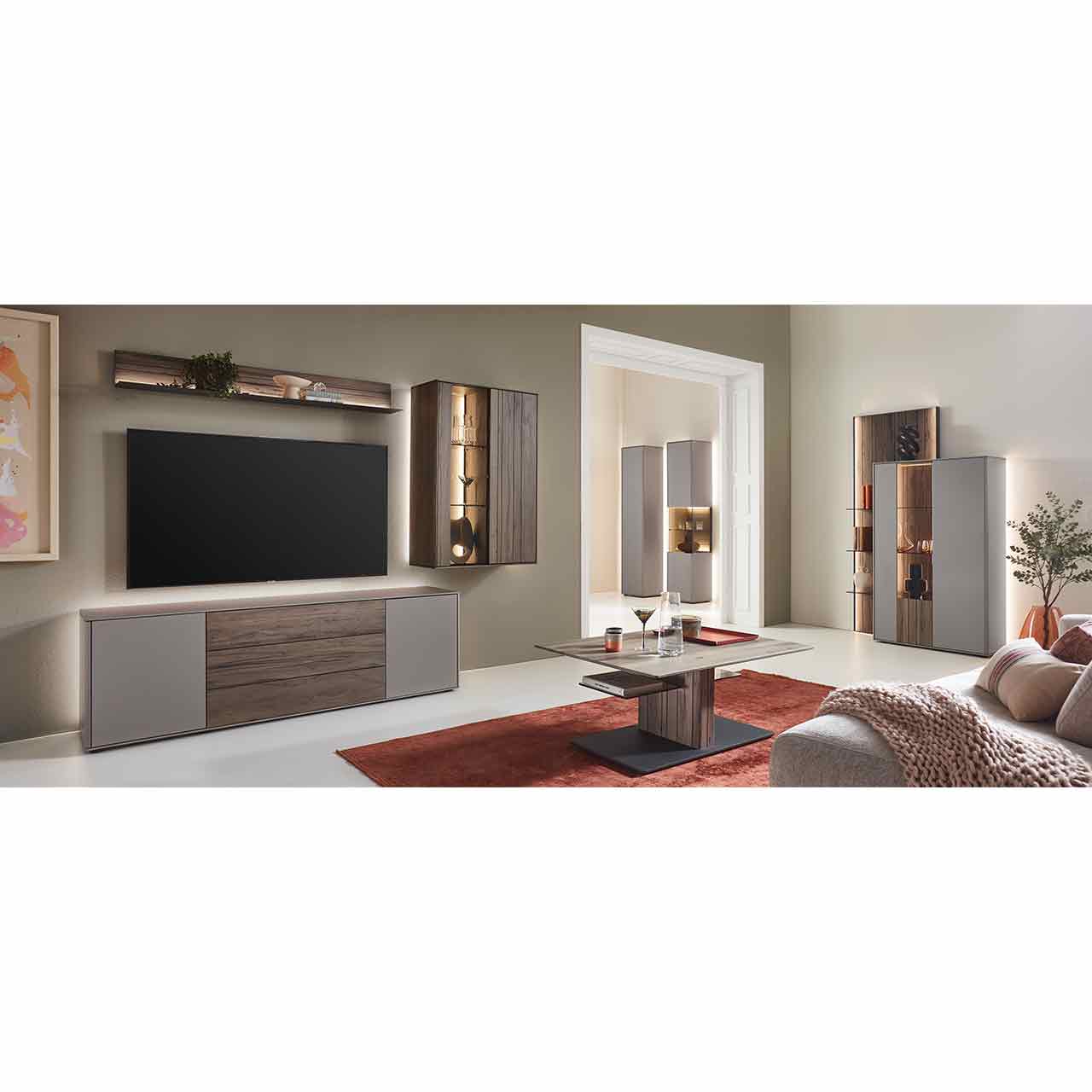 Milieubild - Hartmann AUDRA 5610 - Wohnzimmermöbel aus Altholzbuche Uyaa und Lack Sand Wohnzimmer mit moderner Massivholzwohnwand bestehend aus einem Lowboard in dunkelbraunem Holz und Lack sand, einer beleuchteten Hängevitrine und einem Wandregal in dunkelbraun. Davor rechteckiger Couchtisch, rechts passendes Highboard an Wandpaneel.