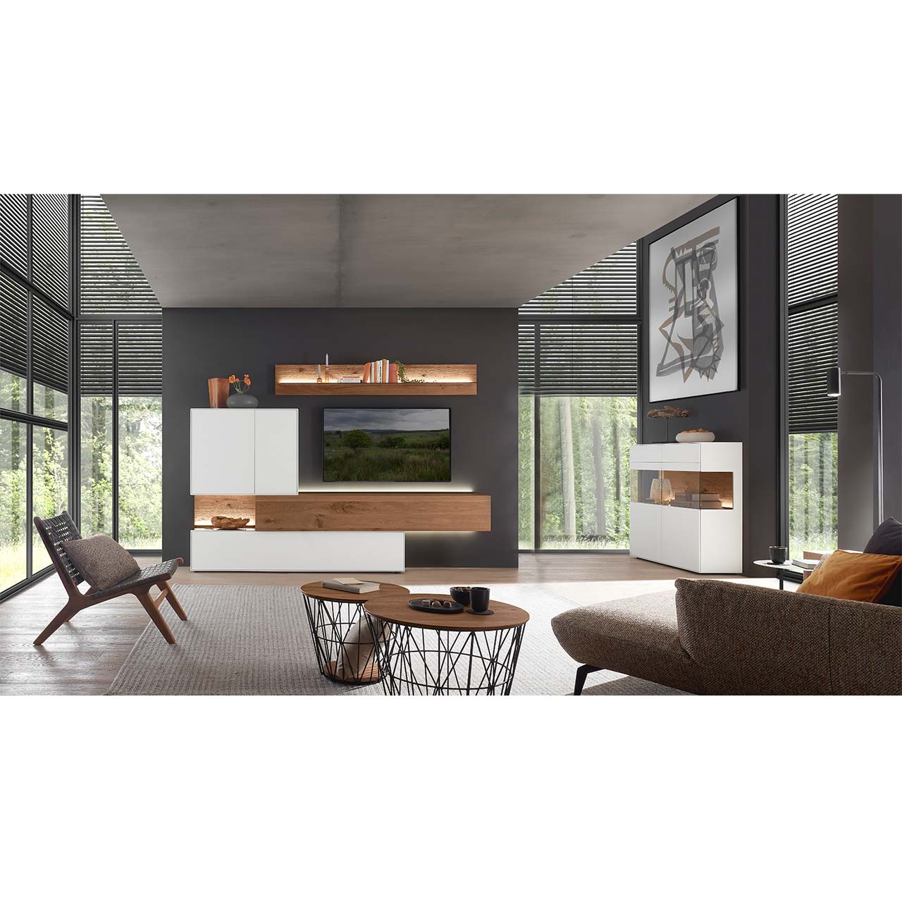 Modernes Wohnzimmer mit Wohnwand aus dunkler Kerneiche und Birke in Lack weiß: Hängelowboard eingefasst in weißen Ober- und Unterschrank darüber Wandpaneel mit Glasablageboden. Rechts an der Wand weißes Highboard, davor zwei runde Couchtische.