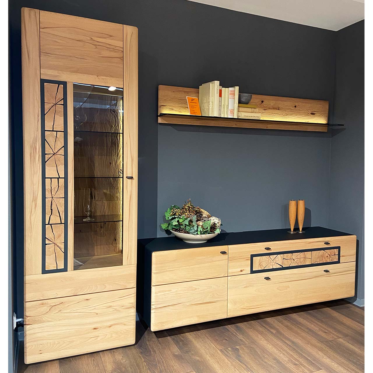Moderne dreiteilige Wohnwand aus massiver Kernbuche gebürstet: Hochvitrine mit Holz/Glastür und Hirnholzscheiben, Lowboard mit Tür und zwei Schubkästen und Hirnholzscheiben, darüber hängendes Wandpaneel mit Glasablage.