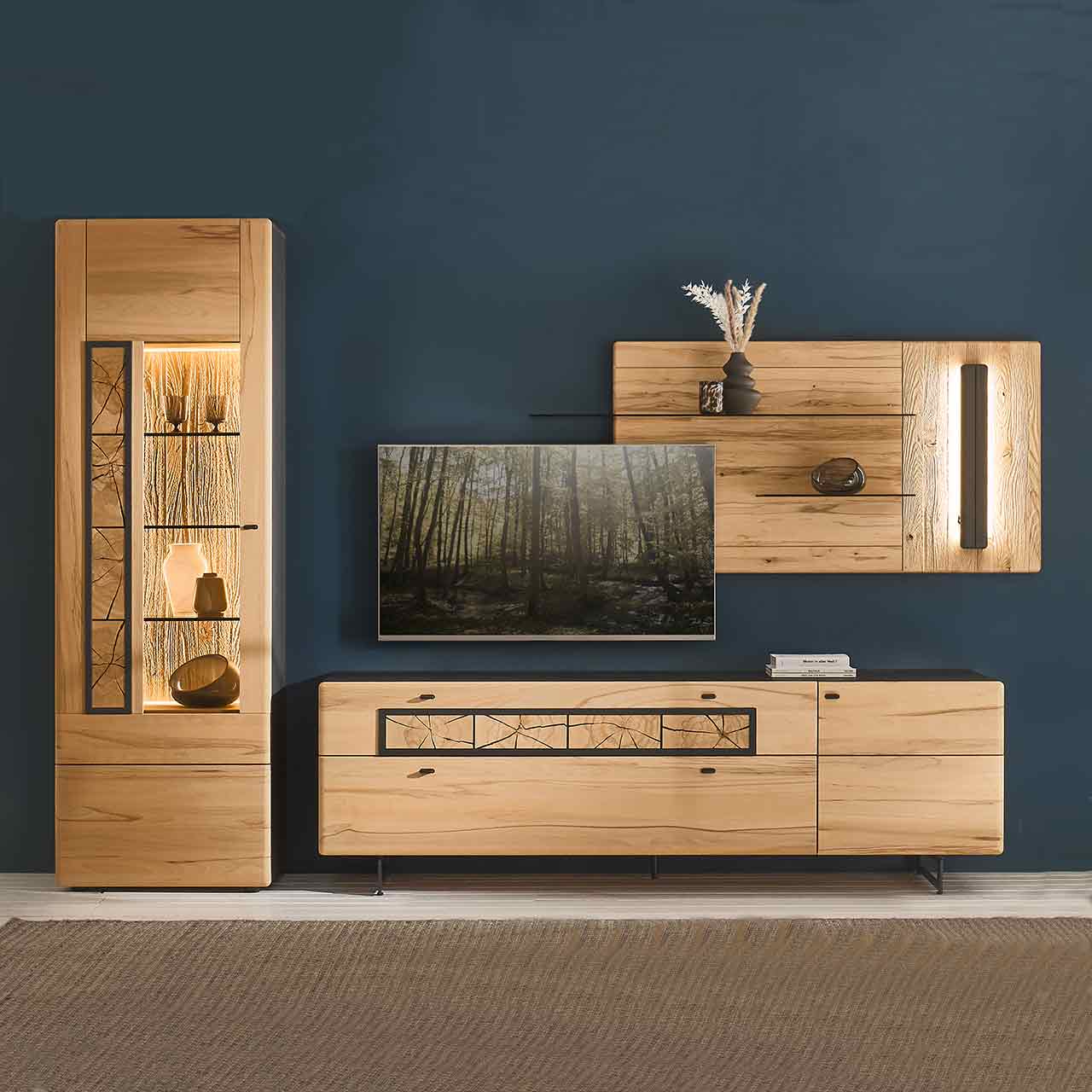 Wohnzimmer - Möbel-Serie Hartmann KNUD 5580 - Wohnwand Nr. 28 Modernes Wohnzimmer mit dreiteiliger Massivholzwohnwand aus heller Kernbuche vor dunkelblauer Wand: Standvitrine mit Hirnholzscheiben, Lowboard auf Metallkufen, Wandpaneel mit anthrazitfarbener Profilleiste und zwei Glasböden.