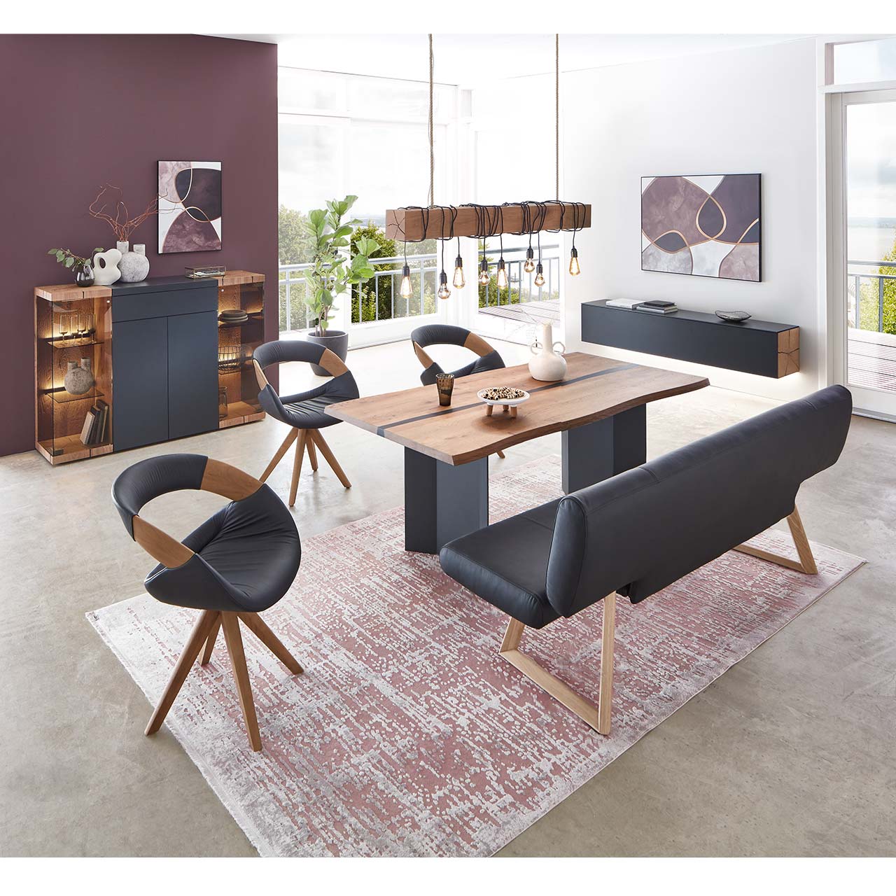 Modernes Esszimmer mit massivem, rechteckigen Holztisch, umgeben von drei Stühlen mit dunkelem Lederbezug auf Holzgestell und der passenden Polstersitzbank. Hinten an der Wand stehend die passenden Esszimmermöbel.