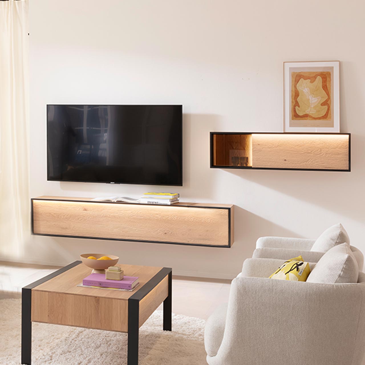 Milieubild - Hartmann YOLA Schöner Wohnen - Wohnkombination 8590 Nr. V26 - zweiteilig Helles Wohnzimmer mit TV und zweiteiliger Wohnwand aus massiver Kerneiche Natur: Hängelowboard und Hängeschrank mit beleuchtetem Glasausschnitt, beide Möbelstücke beleuchtet und eingefasst in Metallrahmen anthrazit. Davor passender Holz-Couchtisch.