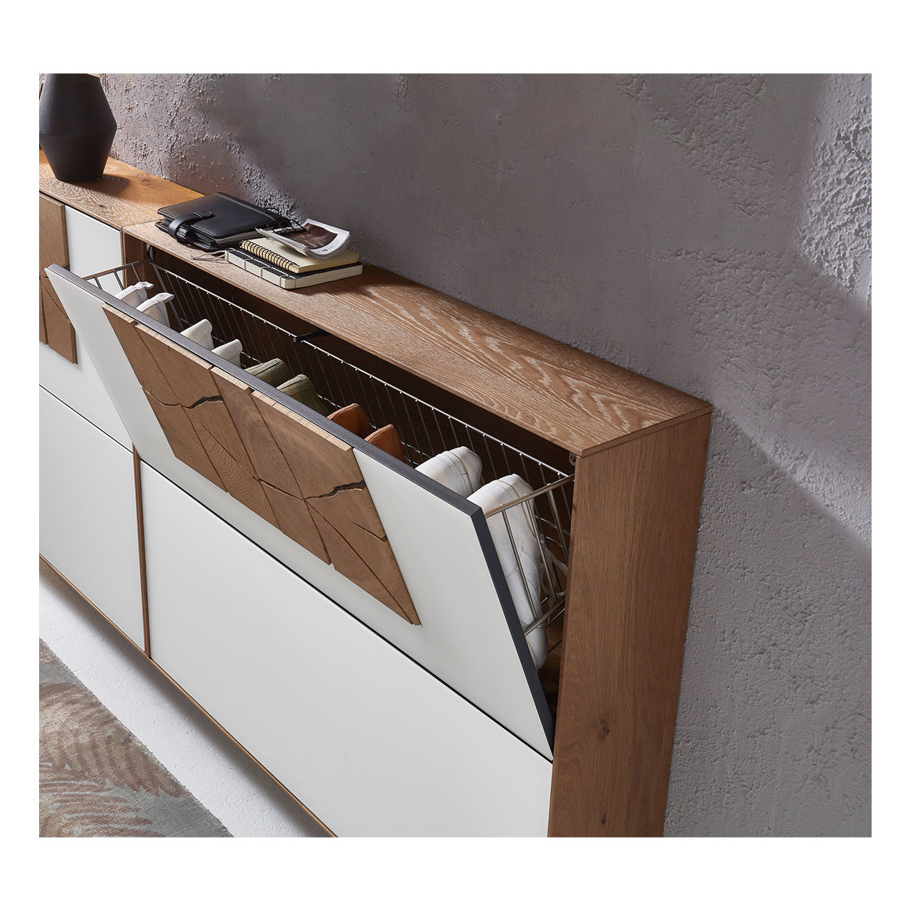 Hartmann CAYA Garderoben - Schuhschrank 7140-4095 - Detail Schuhkorb Zwei Schuhkipper aus massiver Kerneiche Umato mit Mattglas weiß Front und je zwei dekorativen Hirnholzscheiben an oberer Schuhklappe. Die obere Schuhklappe eines Schuhkippers ist geöffnet und zeigt darin einsortierte Schuhe.