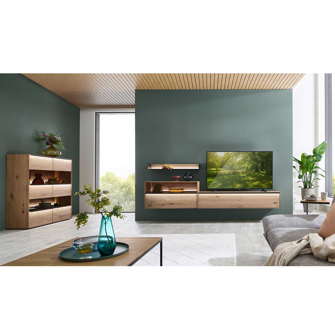 Wohnzimmer mit dunkelgrünen Wänden und natürlichen Massivholzmöbeln