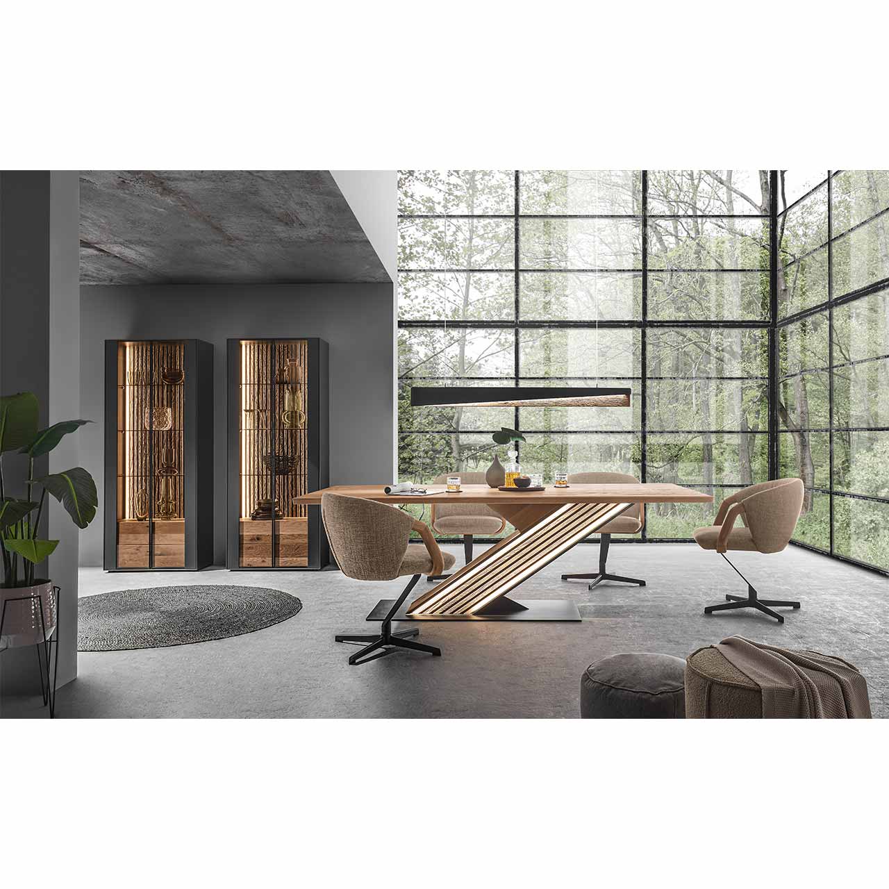 Modern eingerichtetes Esszimmer mit Tisch aus massiver Kerneiche und beleuchteter Lamellensäule, vier beigefarbenen Stühlen mit Metallgestell, darüber eine Balkenleuchte. Im Hintergrund zwei passende Standvitrinen.