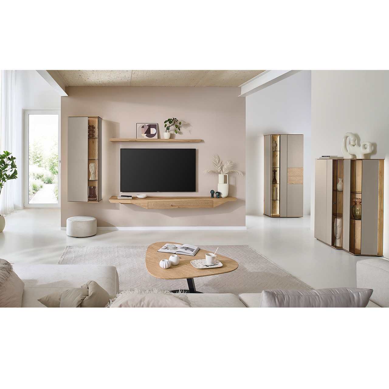 Hartmann Möbel SVEA - Wohnkombination 8660 Nr. V32 - dreiteilig aus Kerneiche Natur, Lack Sand - Milieubild Wohnzimmer mit moderner Massivholzwohnwand bestehend aus Hängelowboard mit Schubkasten, Hängevitrine sowie einem Holzei-Wandboard - im asymmetrischen Design. Rechts passendes Highboard mit Glastüren, davor asymmetrischer Couchtische.