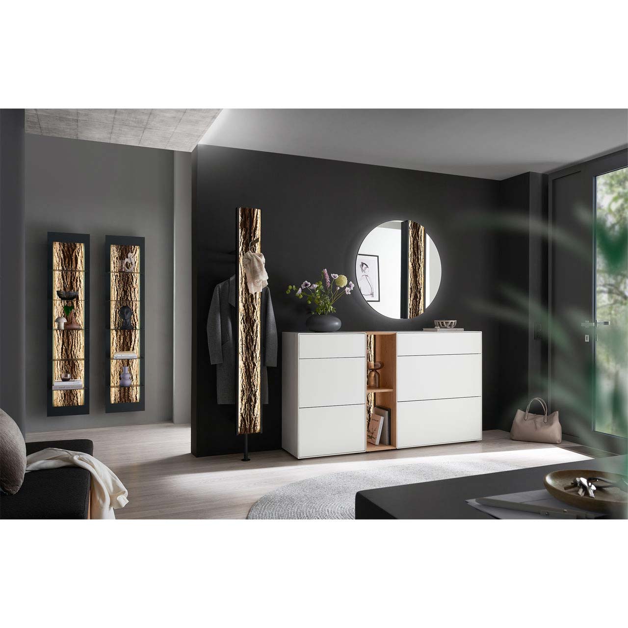 Flur mit modernen Garderobenmöbeln aus Kernbirke und Kerneiche Natur: Regalelement mit Spaltholz-Rückwand zwischen zwei weiß lackierten Stauraumschränken, dazu ein Garderobenpaneel und ein runder Spiegel mit Rinden-Akzent.