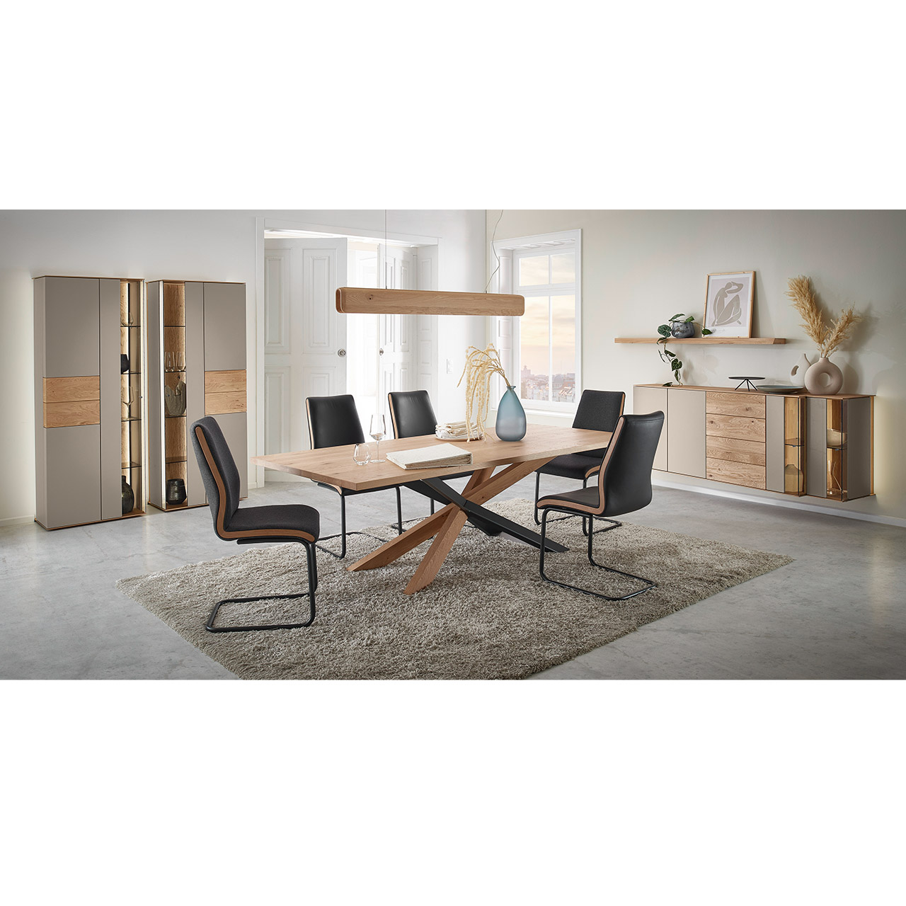 Moderne Esszimmermöbel aus massivem Holz mit Lackfronten in Sand, Parsolglas Bronze und Riffholz: Rechteckiger Holztisch mit Sterngestell, fünf Freischwinger mit dunklem Lederbezug, asymmetrisches Hängesideboard und zwei Standvitrinen in Holz/Lack.