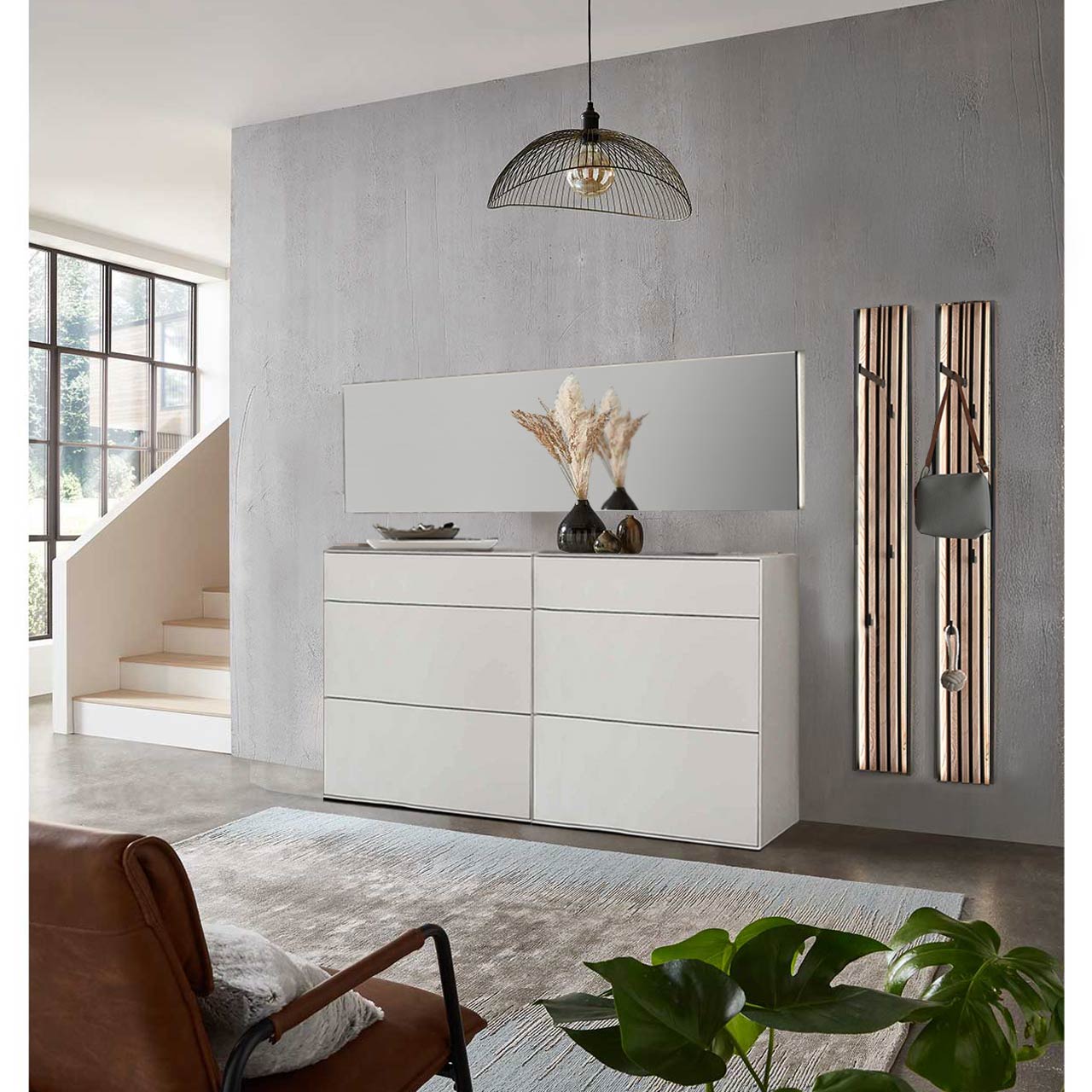 Flur mit modernen Garderobenmöbeln aus massiver Kernbirke in Lack weiß: Zwei Stauraumschränke mit Schubkästen, zwei Garderobenpaneele mit je einer Kleiderstange, vier Mantelhaken und Lamellen-Akzent und ein langer Wandspiegel.