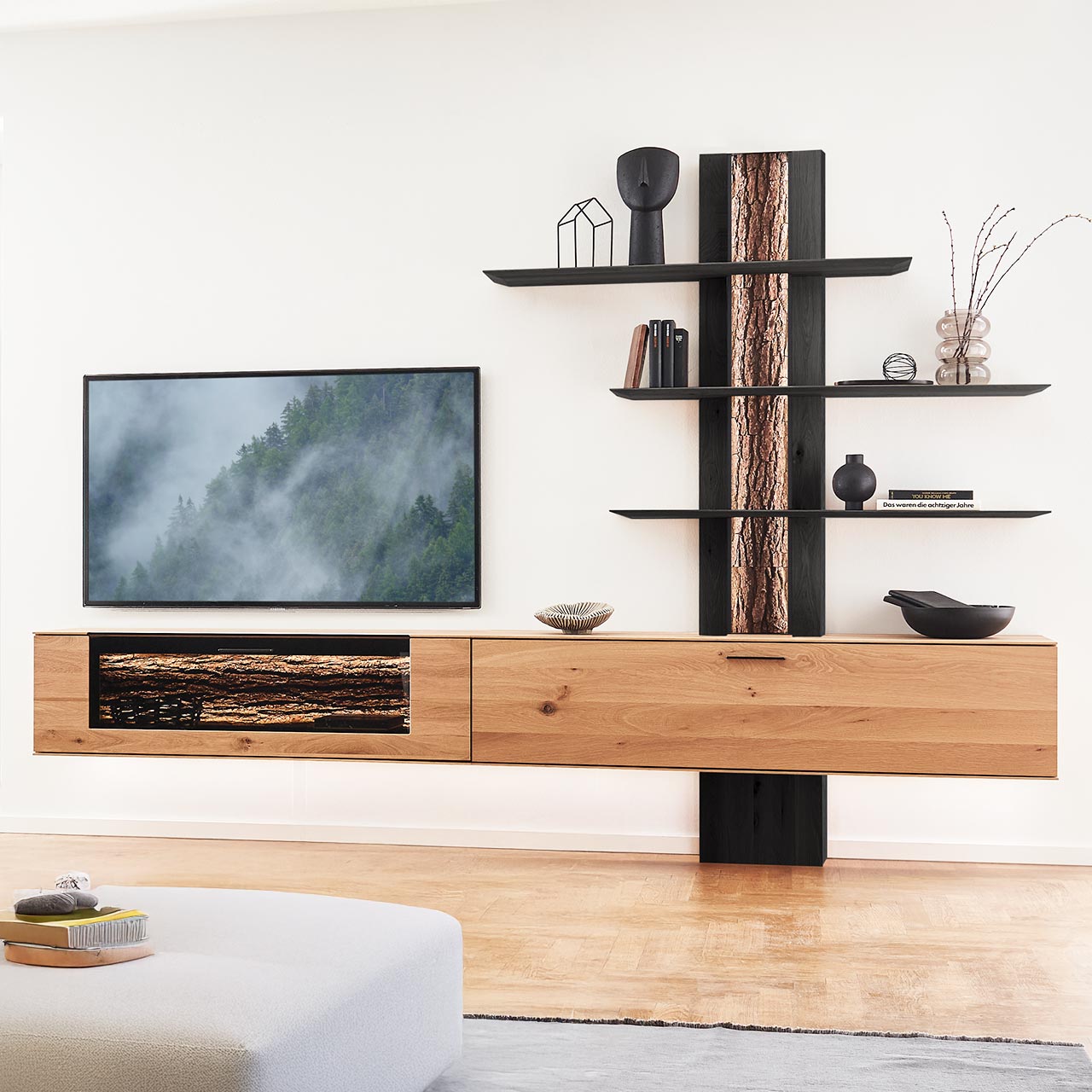 Moderne dreiteilige Wohnwand bestehend aus zwei Hängelowboards aus massiver Kerneiche Natur, eines mit beleuchtetem Glasausschnitt und Rinden-Akzent, und einem Wandpaneel mit sichtbarer Rinden-Rückwand und drei langen, beleuchteten Holzböden. 