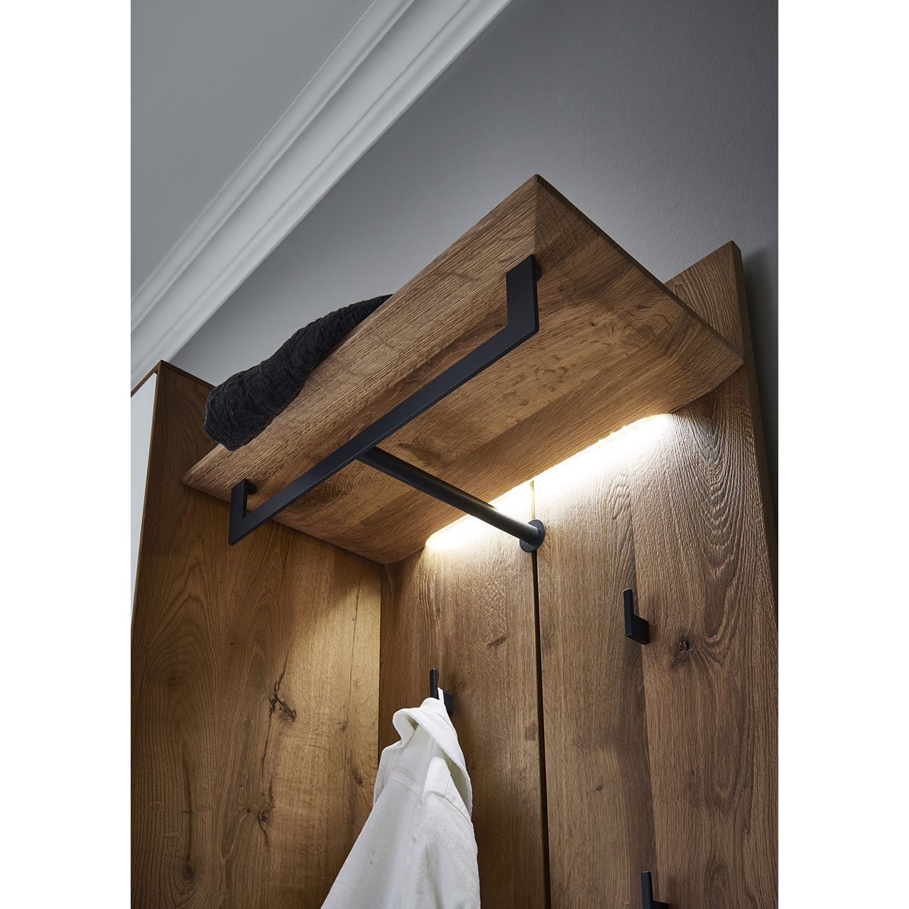 Detailaufnahme der Wandgarderobenbeleuchtung an der Hutablage mit Metallstange vom Garderobenpaneel CAYA 7140-9061 aus massiver Kerneiche - Ansicht von unten.