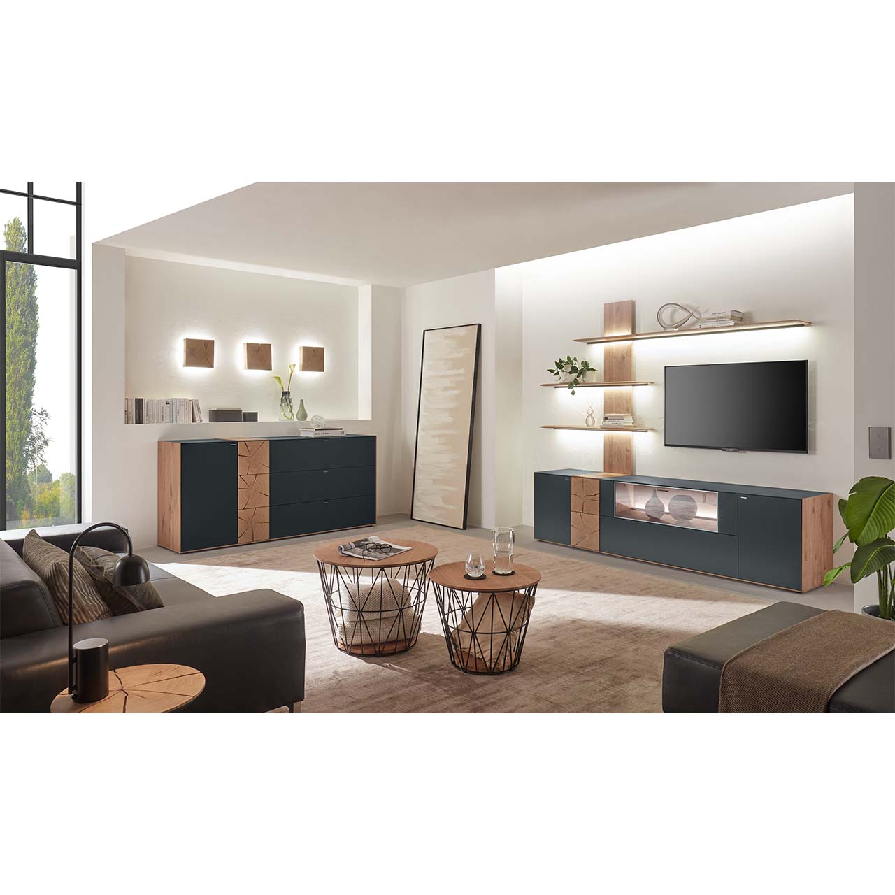Wohnzimmer mit TV und moderner Wohnwand aus massiver Kerneiche mit Hirnholz und Mattglas anthrazit Fronten, mit Lowboard und Wandpaneel mit Regalböden. Links das passende Sideboard, darüber drei Holzwand-Leuchten. Im Vordergrund zwei runde Couchtische.