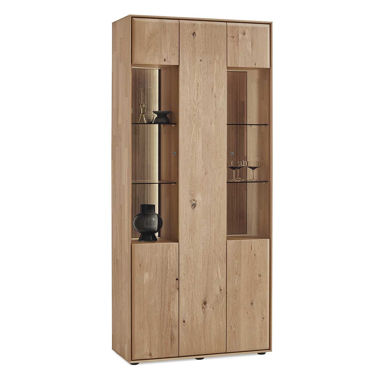 Hartmann VALA - Standvitrine 8640-0091 - Kerneiche Natur / Glas Moderne 3-türige Standvitrine aus massivem Eichenholz mit 2 Glastüren rechts und links und einer Holztür mittig - in Seitenansicht.