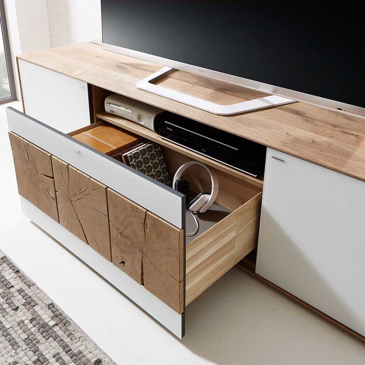 Detailbild des CAYA Lowboards Nr. 7170-2225W aus massiver Kerneiche Untao mit Mattglas weiß Front mit geöffnetem Schubkasten. Schubkastenfront versehen mit drei dekorativen, rechteckigen Hirnholzscheiben in Kerneiche Umato. 