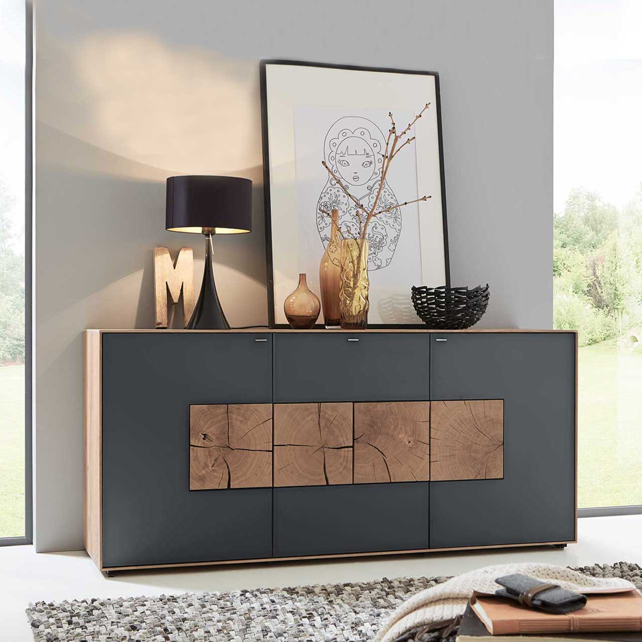 Flur mit modernem Sideboard aus massiver Kerneiche Umato mit anthrazitfarbenen Mattglasfronten und vier dekorativen, rechteckigen Hirnholzscheiben - vor hellgrauer Wand.