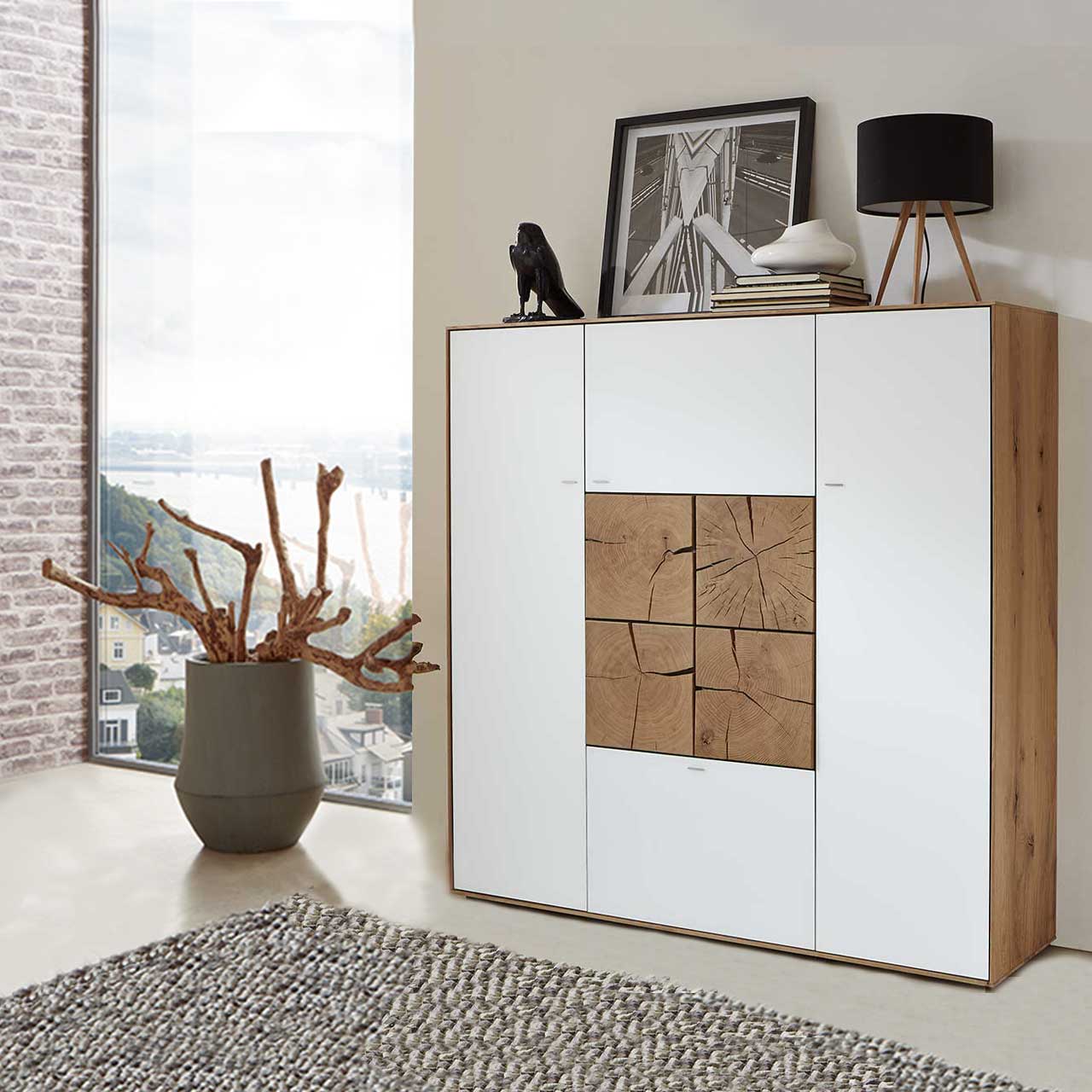 Modernes Highboard aus massiver Kerneiche Umato mit Mattglas weiß Fronten und vier in der Mitte zum Quadrat zusammengesetzten, dekorativen Hirnholzscheiben in Kerneiche Umato - in einem moderne Flur stehend.