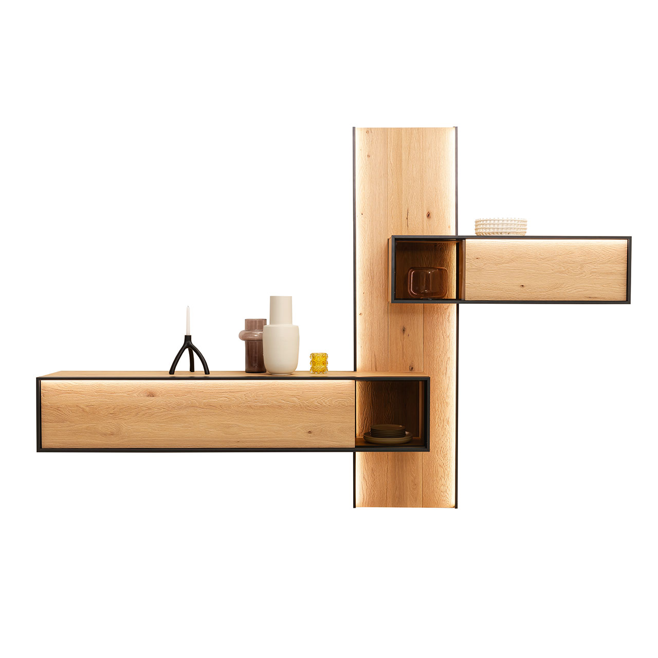 Minimalistische Wohnwand aus massiver, sandgestrahlter Kerneiche Natur mit anthrazitfarbenem Metallrahmen, bestehend aus langem, beleuchtetem Wandpaneel, oben seitlich angebrachtem Hängeregal mit Glasausschnitt und Lowboard mit Glasdetail unten.