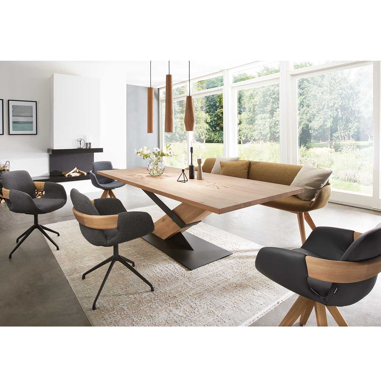 Modernes Esszimmer mit massivem Holztisch, drei Drehstühlen mit dunkelgrauem Stoffbezug auf Metallgestell und einer Sitzbank in Senfgelb mit zwei passenden Kissen. Über dem Tisch hängen drei Pendelleuchten mit Lampenschirmen aus Holz.