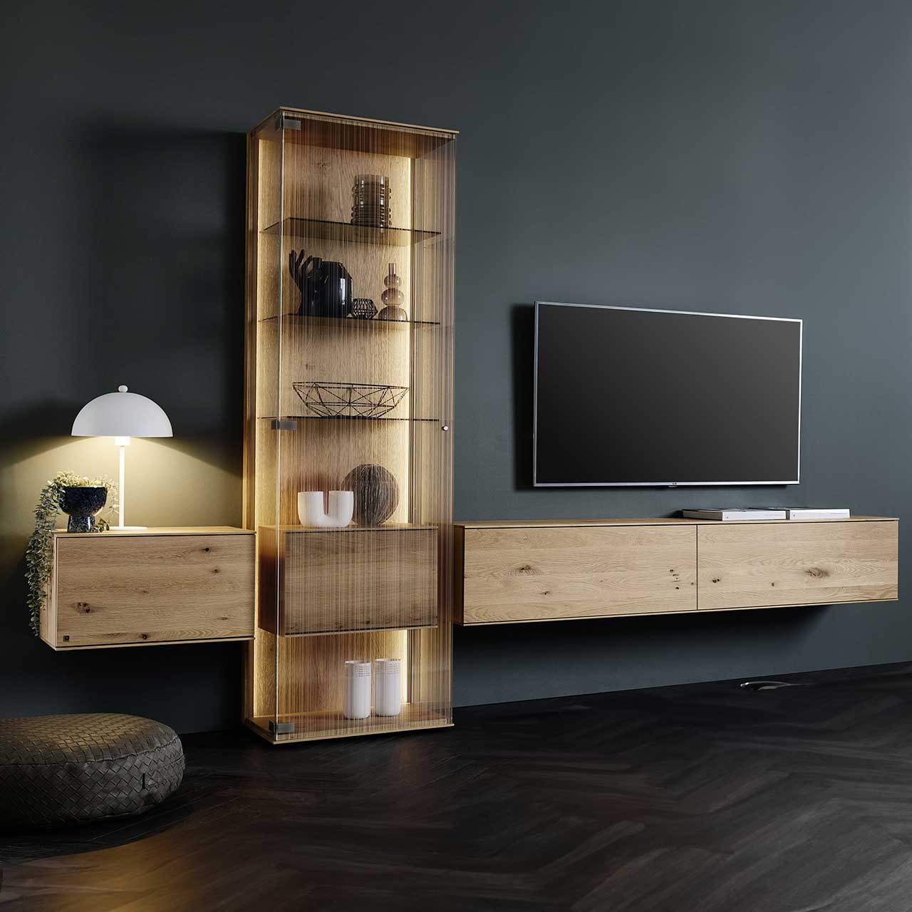 LINEA Leonardo Living - Wohnwand 8540 Nr. SV20 Modernes Wohnzimmer mit Fernseher und dreiteiliger Wohnwand aus Kerneiche Natur: Zwei schlichte Hängelowboard und Standvitrine mit satiniertem Glas und innenliegendem Holzkorpus mit Klappe – platziert vor einer dunklen Wand.