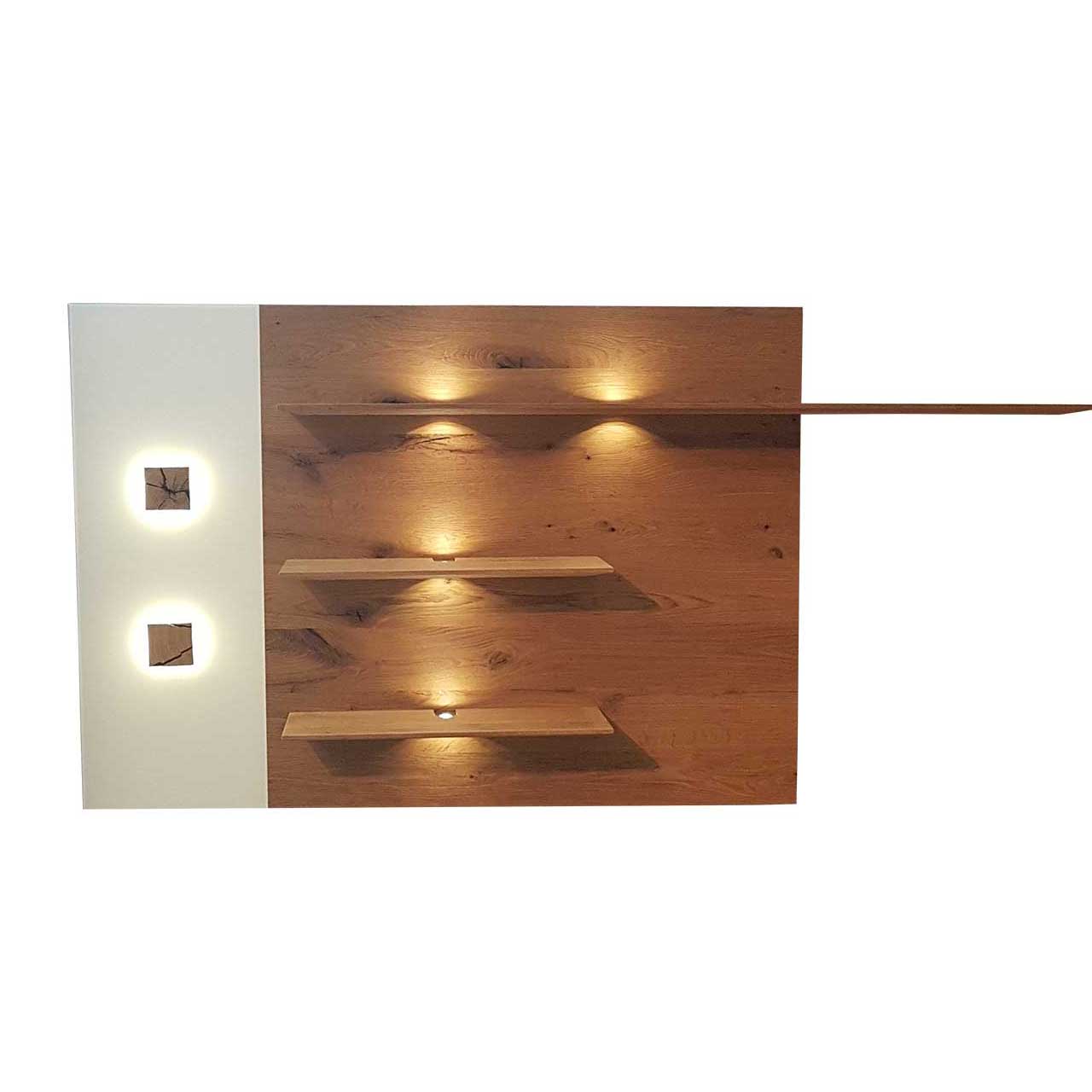 Hartmann CAYA - Wandpaneel 7170-5185W Modernes Wandpaneel aus massiver Kerneiche Umato mit drei, beleuchteten Ablageböden, links mit Mattglas weißer Applikation und zwei kleinen, rechteckigen Hirnholzscheiben.