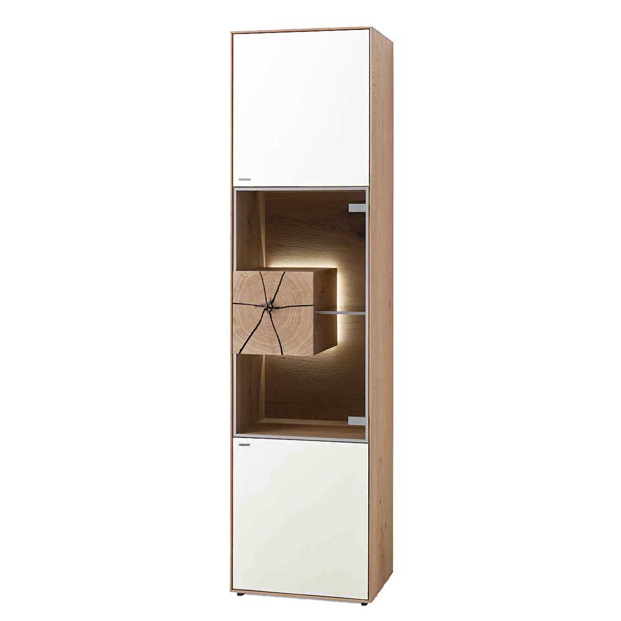 Hartmann CAYA - Standvitrine 7170-0056W - Türanschlag rechts Moderne Standvitrine aus massiver Kerneiche Umato mit Mattglas weiß Front, mittig mit beleuchtetem Glasausschnitt, Glasboden und Hirnholzblock aus hellem Holz.