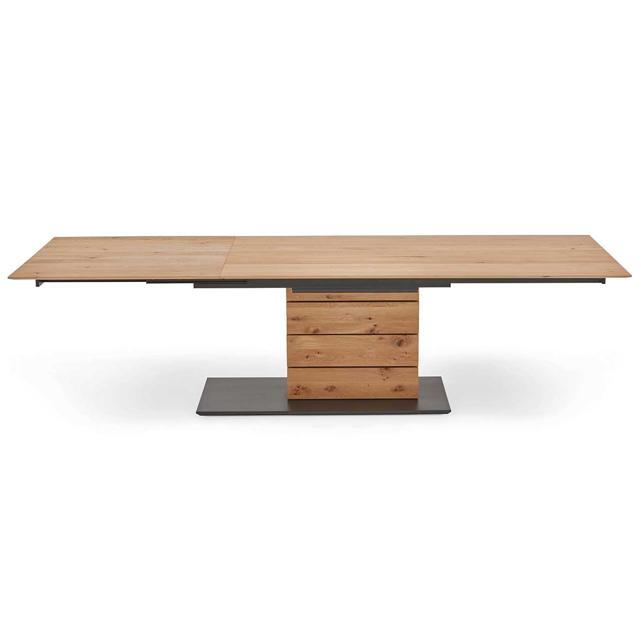 Hartmann NATURZEIT 7100E/8400E - 1552 Esstisch T100 - ausgezogen Moderner Esstisch aus massiver Kerneiche mit ausgezogener, rechteckiger Tischplatte mit Säule aus vier massiven Holzblöcken und rechteckiger Bodenplatte in der Farbe anthrazit.