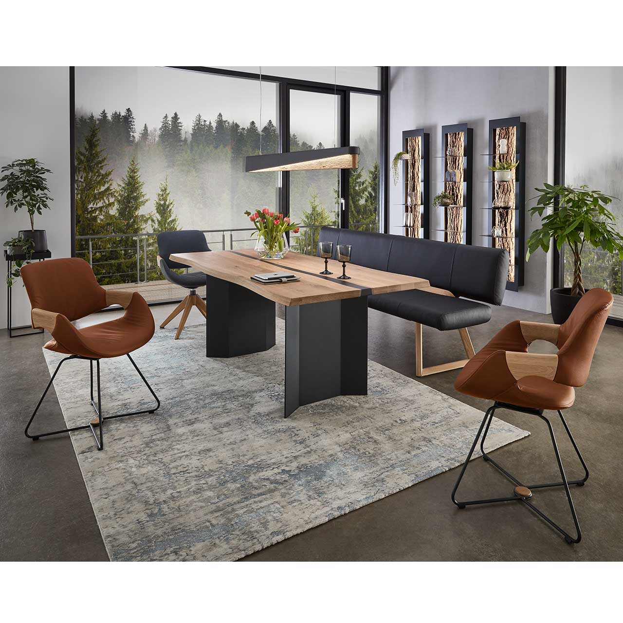 Modernes Esszimmer mit rechteckigem Holztisch umgeben vor drei Stühlen und passender Sitzbank. Darüber hängend eine Paneel-Pendelleuchte aus massivem Holz mit Teileinfassung in Metall Anthrazit. 