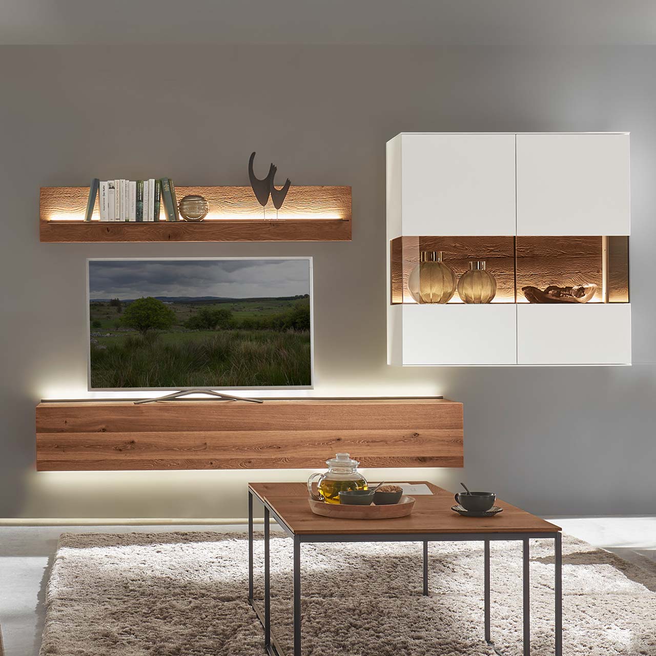 Hartmann TORIDO - Wohnwand 7270 Nr. V26 - dreiteilig - Birke Lack weiß & Kerneiche Umato Moderne, dreiteilige Massivholz-Wohnwand aus dunkler Kerneiche und weiß lackierten Elementen, bestehend aus Hängelowboard, Wandregal mit Glasablageboden und quadratischer Hängevitrine in Lack weiß mit mittigem, beleuchtetem Glasausschnitt.