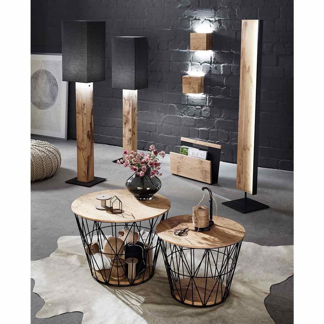 Milieubild Wohnzimmer - Hartmann NATURSTÜCKE 7610-1064, 1052/1053, 1071/1072 Zwei Stehlampen mit Stofflampenschirm und Holzfuß, zwei Wandlampen mit Holzkorpus, ein Holz-Zeitungsständer, eine Holzstehlampe. Davor zwei runde Couchtische mit feinem Metallkorb in Anthrazit und abnehmbarem Holzdeckel - im Wohnzimmer stehend.
