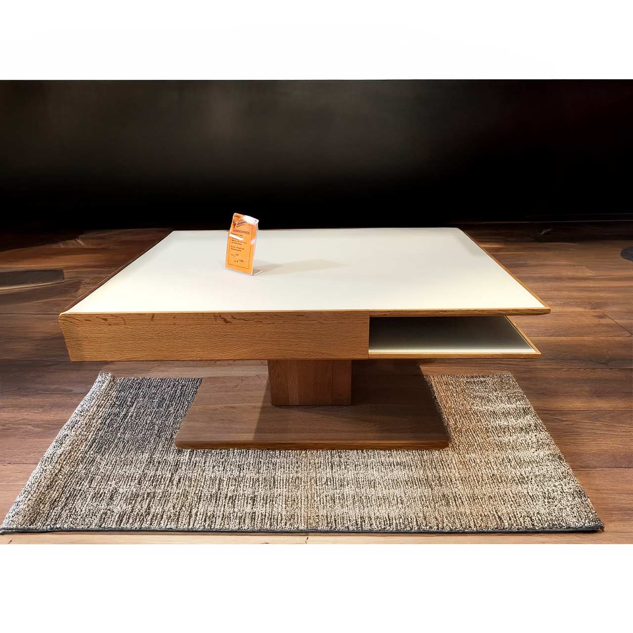 Hartmann SALE Möbel - CAYA Couchtisch 7170-0447 - inkl. Beleuchtung / Originalbild Ausstellung Moderner, rechteckiger Couchtisch aus massiver Kerneiche Umato. Dicke Tischplatte in Mattglas weiß mit integriertem Schubkasten und seitlichem Ablagefach, auf massiver, rechteckiger Holzsäule und Bodenplatte stehend.