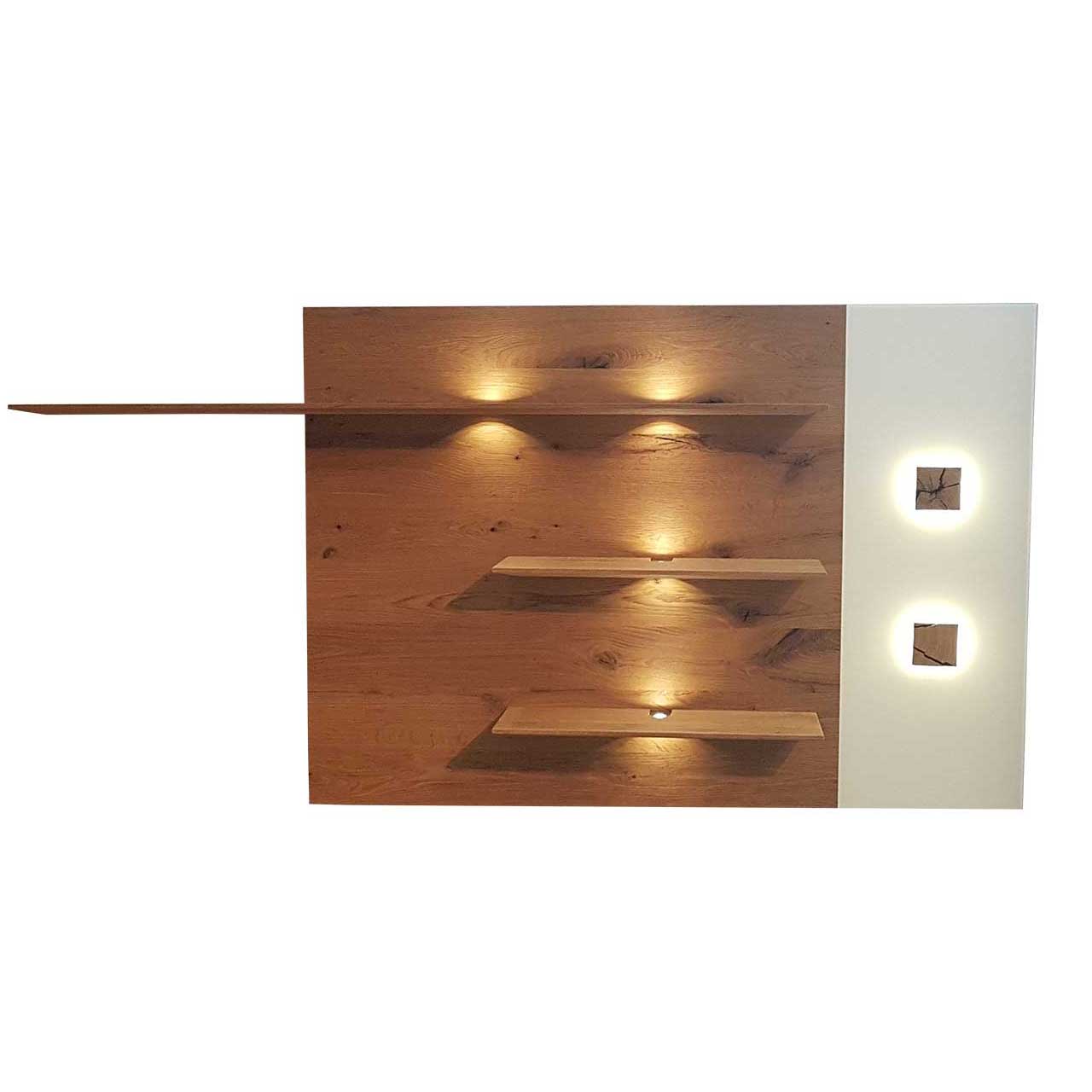 Hartmann CAYA - Wandpaneel 7170-5186W Modernes Wandpaneel aus massiver Kerneiche Umato mit drei, beleuchteten Ablageböden, rechts mit Mattglas weißer Applikation und zwei kleinen, rechteckigen Hirnholzscheiben.