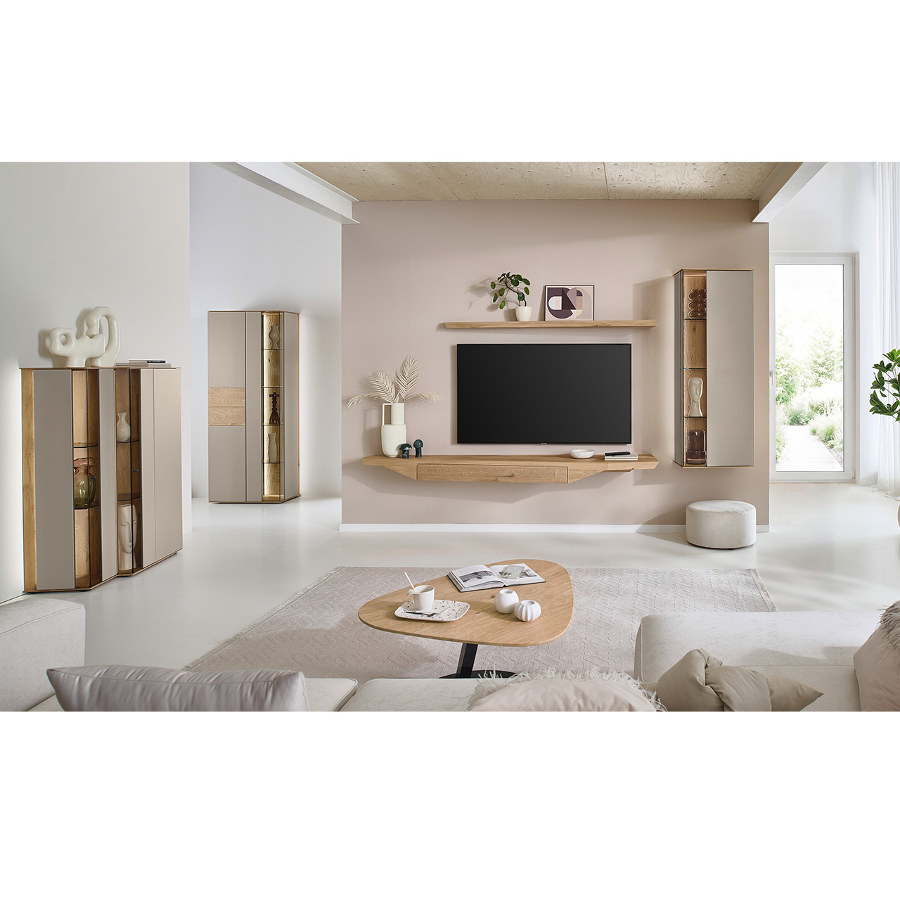 Hartmann Möbel SVEA - Wohnkombination 8660 Nr. V32 SV - dreiteilig aus Kerneiche Natur, Lack Sand - Milieubild Wohnzimmer mit moderner Massivholzwohnwand bestehend aus Hängelowboard mit Schubkasten, Hängevitrine sowie einem Holzei-Wandboard - im asymmetrischen Design. Links passendes Highboard mit Glastüren, davor asymmetrischer Couchtische.
