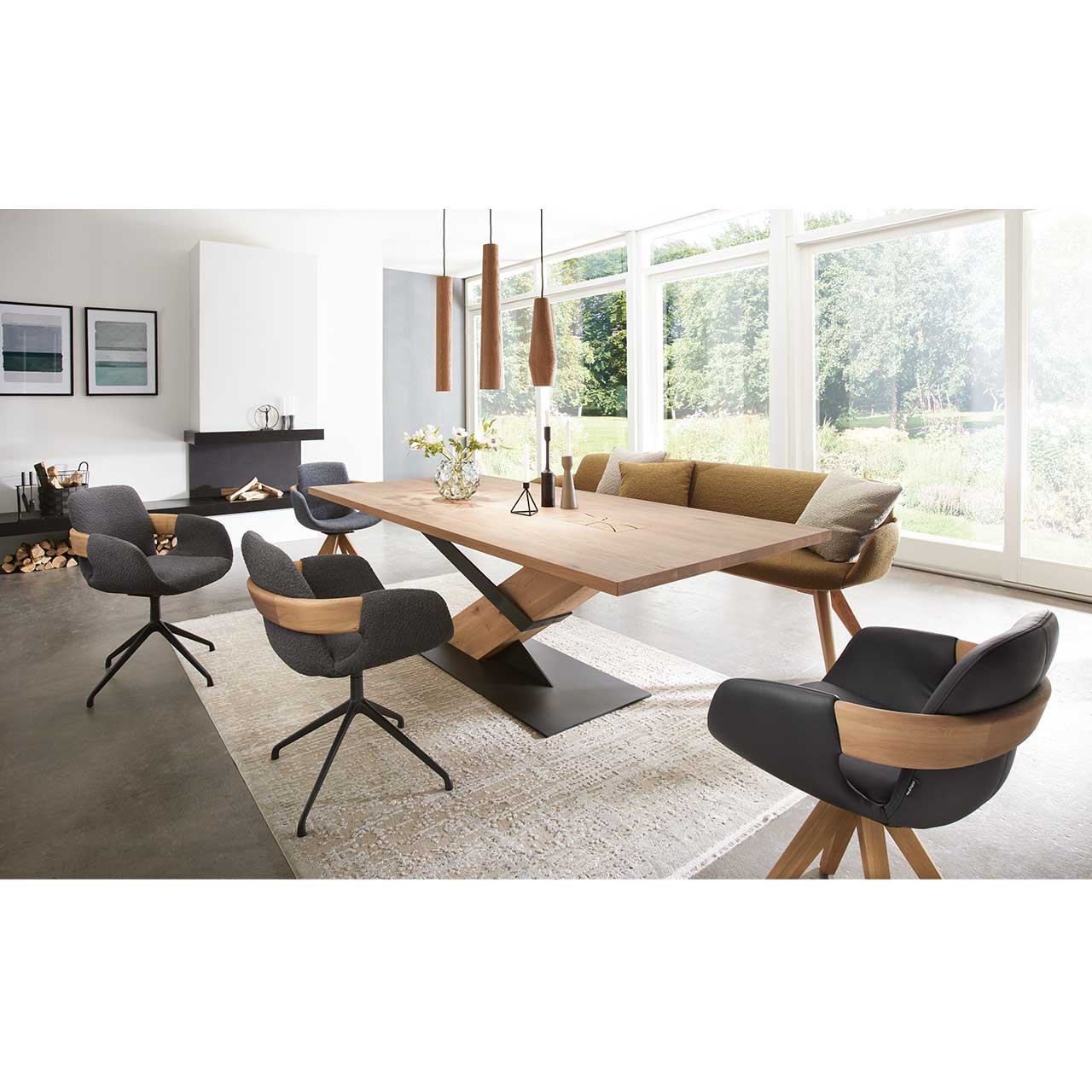 Milieubild Esszimmer - Hartmann NATURZEIT 7100E/8400E - 1648 Stuhl Emil Comfort Modernes Esszimmer mit massivem, rechteckigen Holztisch, umgeben von vier Stühlen mit Holz- und Metallgestell und passender Polstersitzbank. Über dem Tisch hängen drei Pendelleuchten mit zylinderförmigen Lampenschirmen aus Holz.