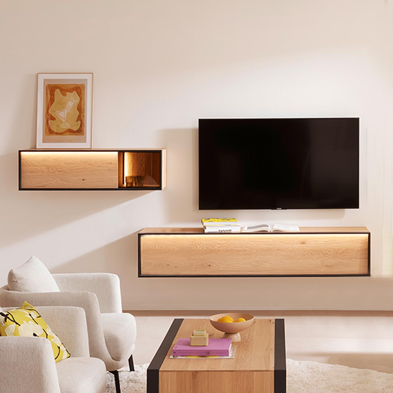 Hartmann YOLA Schöner Wohnen - Wohnkombination 8590 Nr. V26SV - zweiteilig Helle zweiteilige Wohnwand aus massiver Kerneiche Natur: Hängelowboard und Hängeschrank mit beleuchtetem Glasausschnitt, beide Möbelstücke beleuchtet und eingefasst in Metallrahmen anthrazit. Davor passender Holz-Couchtisch.