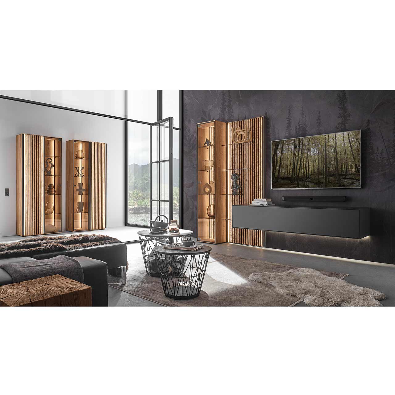 Modern eingerichtetes Wohnzimmer mit fünfteiliger Wohnwand in Anthrazit kombiniert mit hellem Holz und Lamellen. Rechts das passendem Highboard. Im Vordergrund heller Couchtisch, im Hintergrund zwei helle Standvitrinen mit Lamellen.