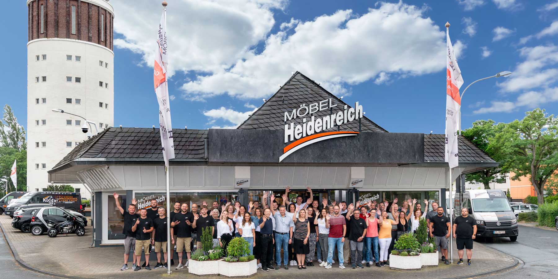 Gruppenfoto - Mitarbeiter MöbelHeidenreich Gruppenfoto der Mitarbeiter vor dem Möbelhaus Heidenreich in Groß-Gerau. Im Hintergrund links steht der bekannte Wasserturm.