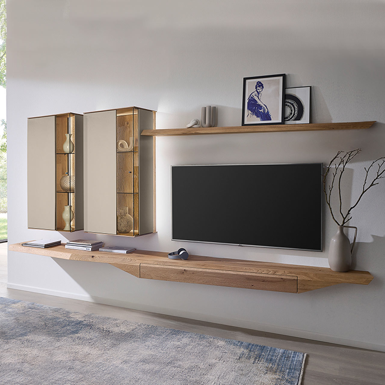 Moderne, vierteilige Wohnwand aus massiver Kerneiche Natur mit Lack Sand und Riffholz im asymmetrischen Design. Bestehend aus Hängelowboard mit Schubkasten, zwei Hängevitrinen in Holz/Lack sowie einem Wandboard aus Riffholz.