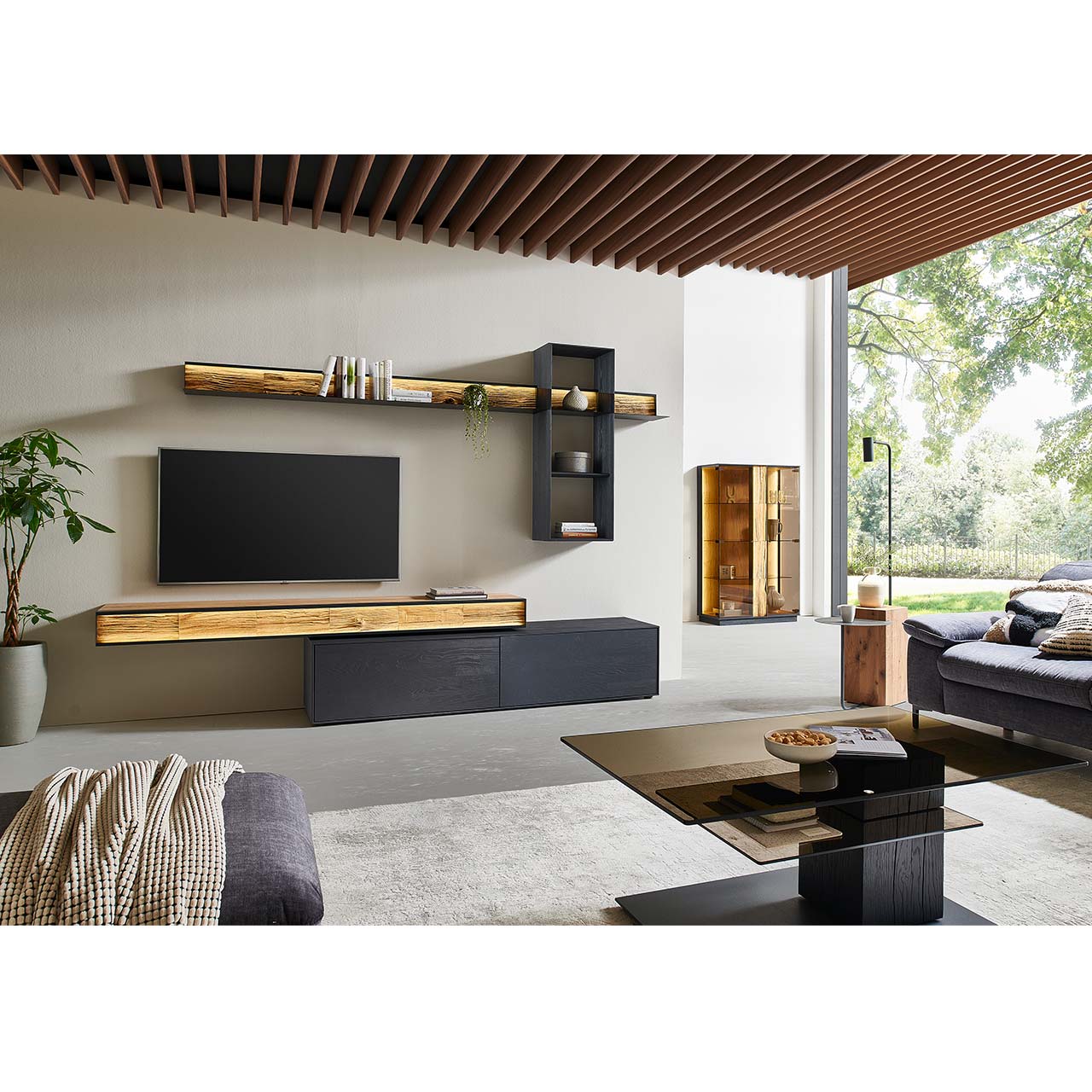 Moderne Wohnwand mit Materialmix aus Lack anthrazit mit Spaltholz-Akzenten und Parsolglas-Vitrinenausschnitten